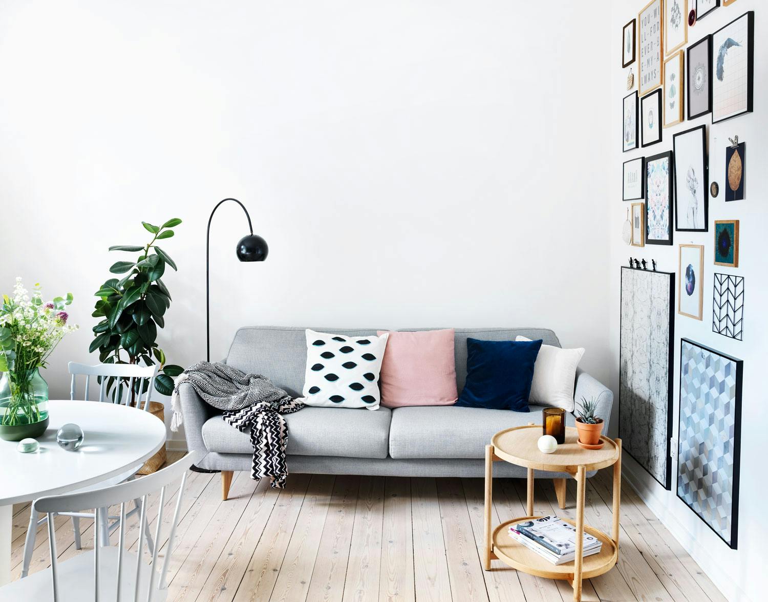 Bruktfunn og budsjettkupp Grå retrosofa i lys stue med grønne planter og leken bildevegg